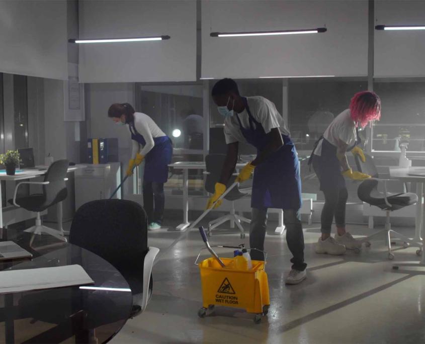 janitors in safety mask mop floor and disinfect furniture in empty office