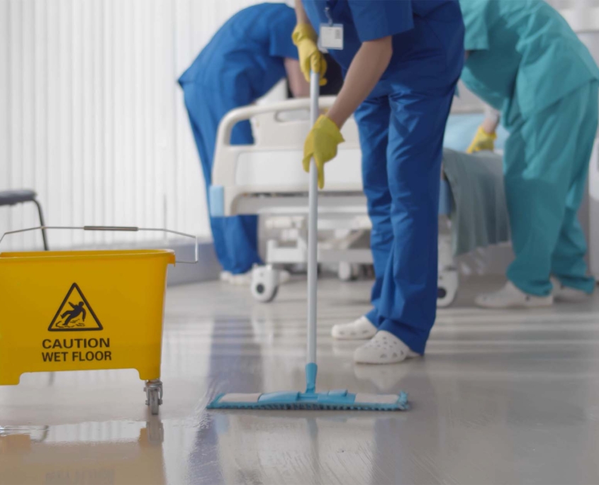 person cleaning floor in a hospital room with wet floor sign