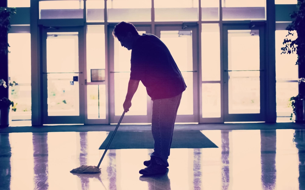 Worker mopping entrance of commercial building