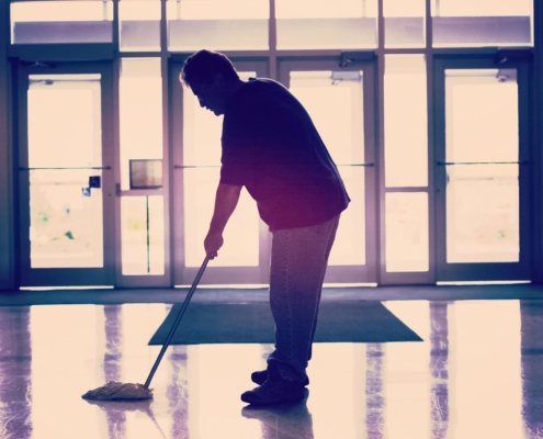 Worker mopping entrance of commercial building