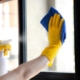 Close up of a person in yellow gloves cleaning a window