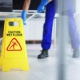 Front view of a wet floor sign with a custodian behind it