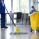 Side view of a custodian mopping the floor with janitorial equipment in the frame