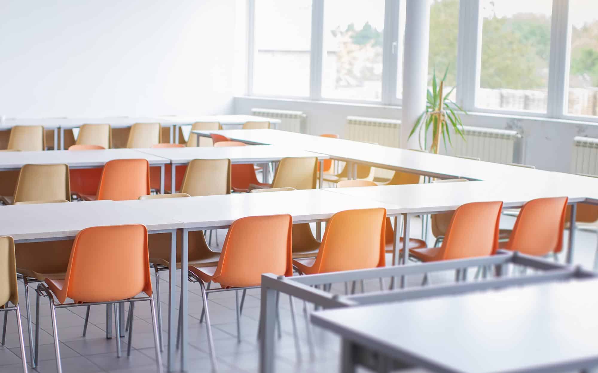 Side view of a row of tables with orange chairs