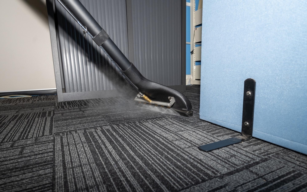 Person steam cleaning carpet in commercial building