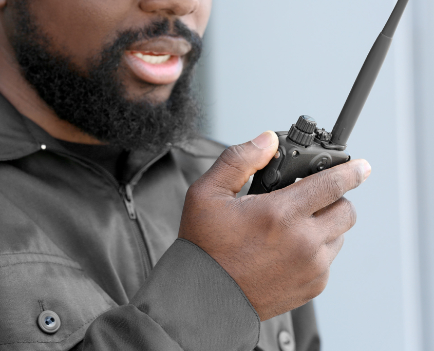 Male security guard using portable radio transmitter outdoors